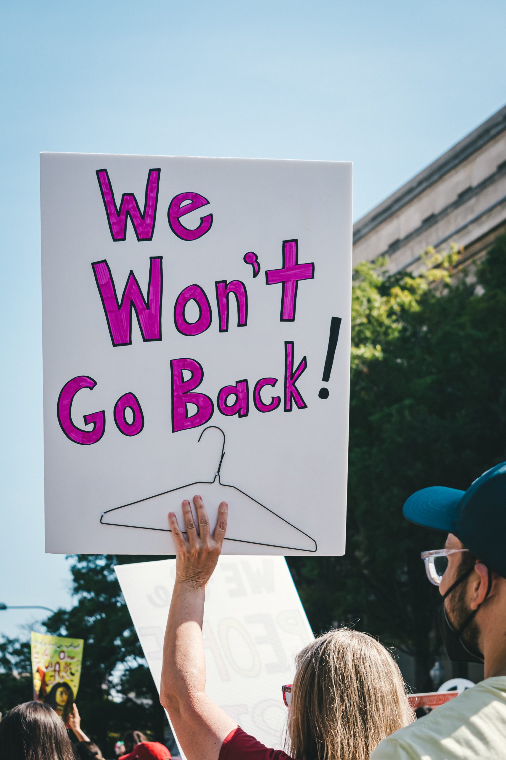 Protest sign that says "we won't go back" and has a picture of a coat hanger