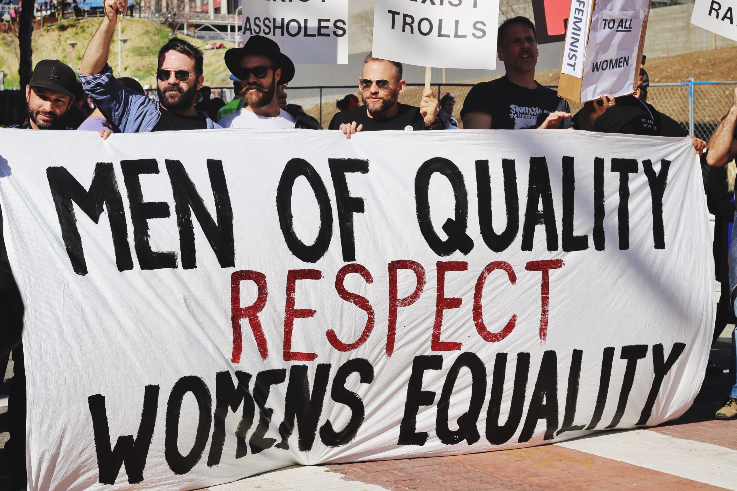Men holding large sign that says "men of quality respect women's equality"