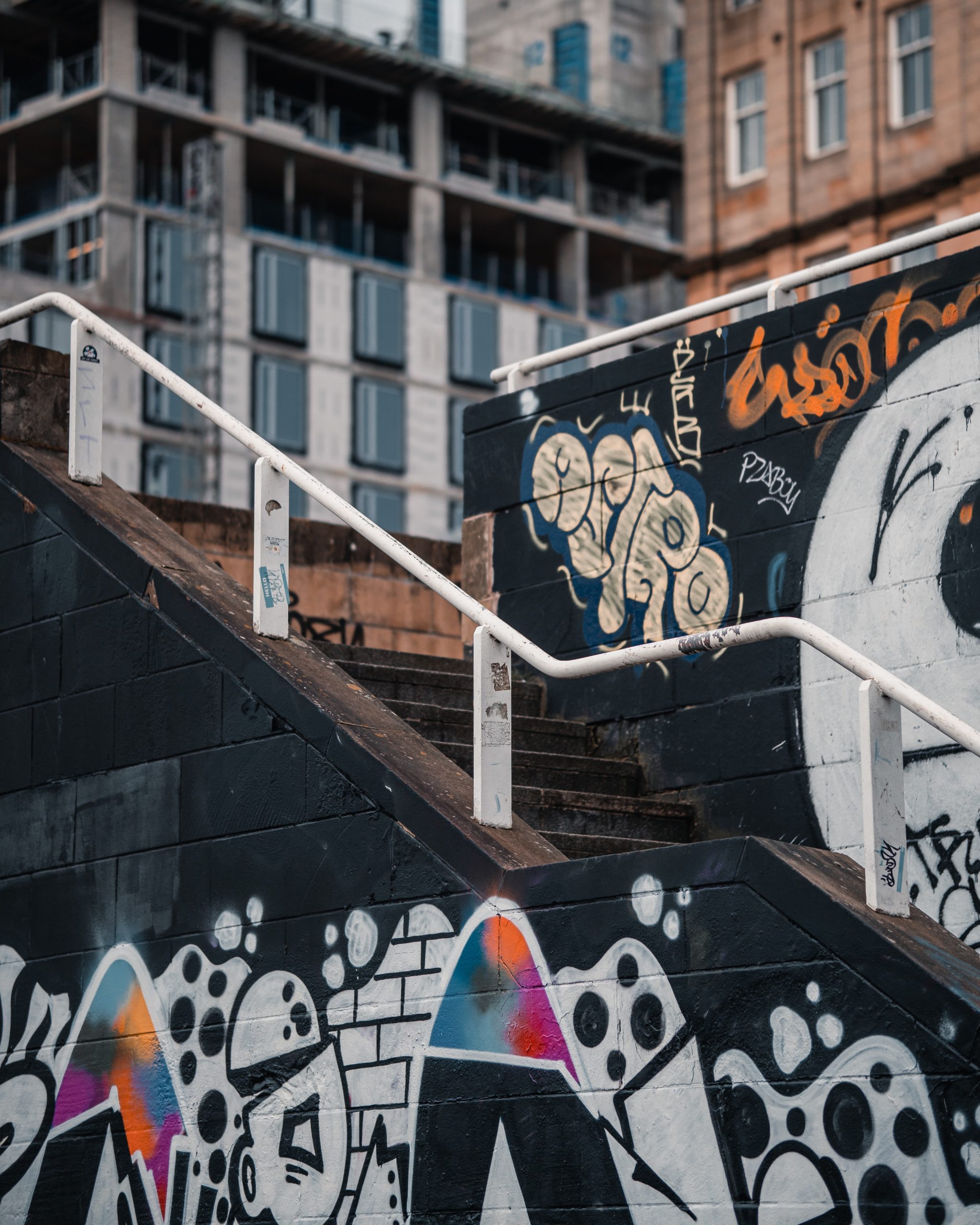 Urban stairway in Glasgow with street art on black walls with white and multicolor designs 