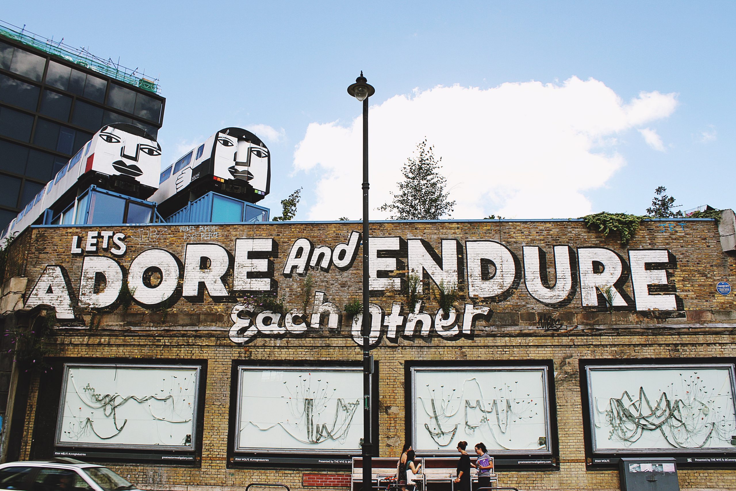 External of brick building with painted words reading "Adore and Endure Each Other" in London
