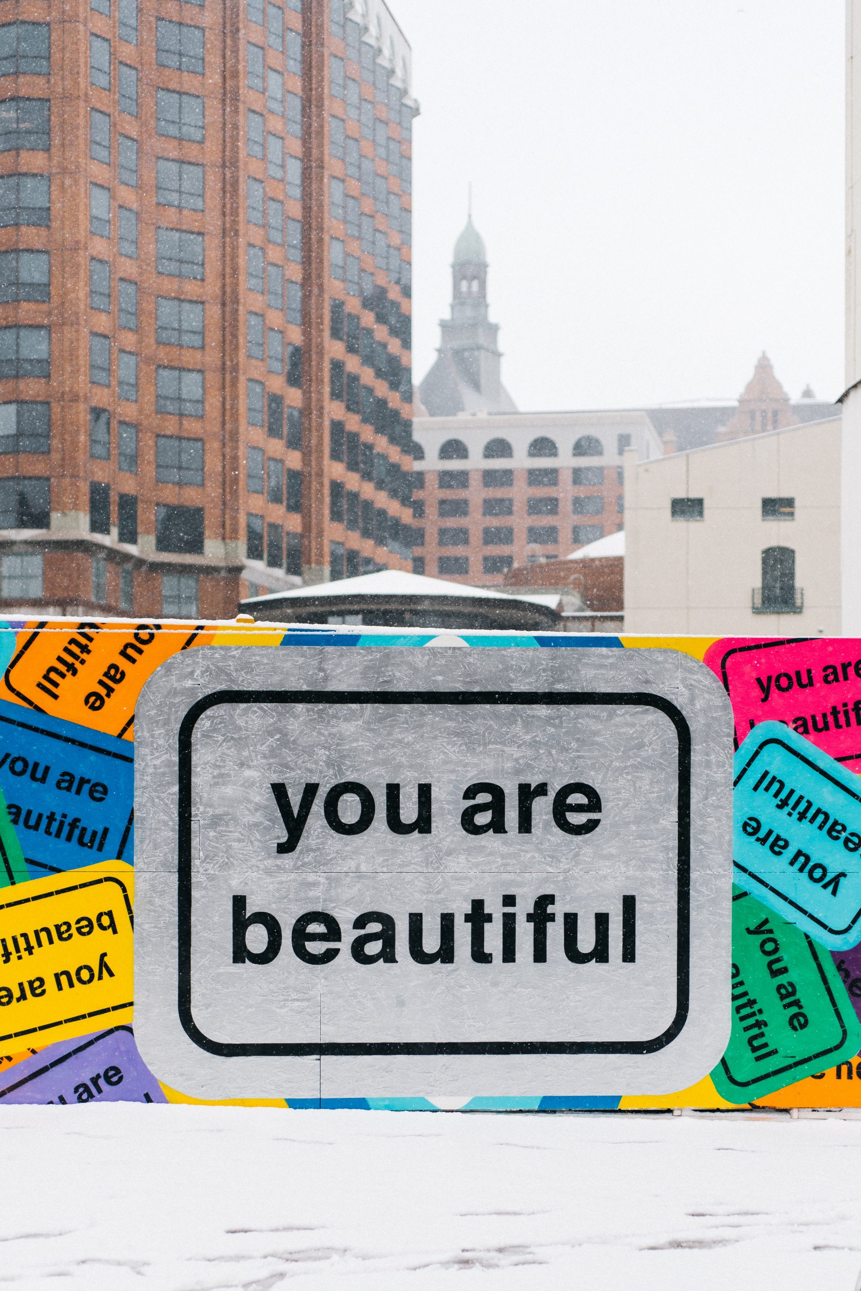 Urban wall displaying multiple large stickers that read "You are beautiful" in Milwaukee, WI