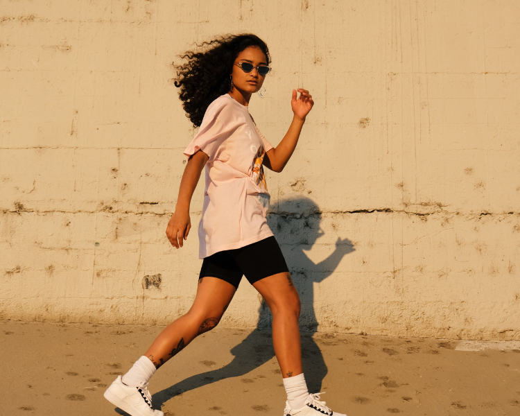 girl walking alongside beige concrete wall