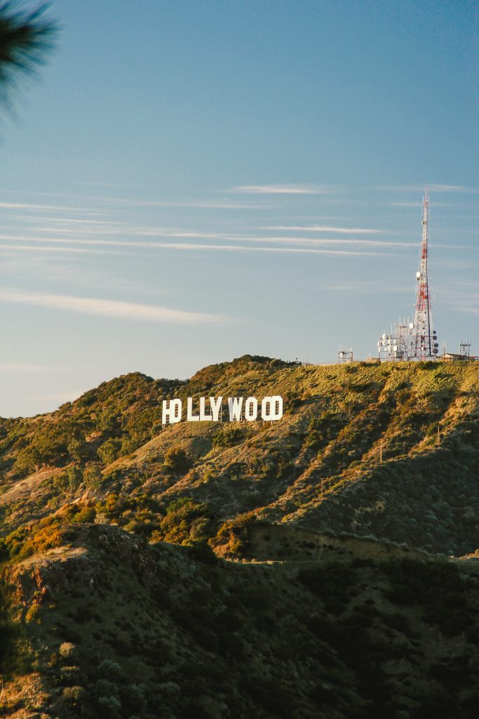 red and white tower and white hollywood sign on hill at dusk