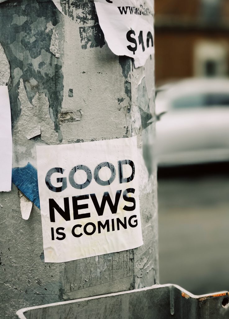 white good news is coming poster on street post